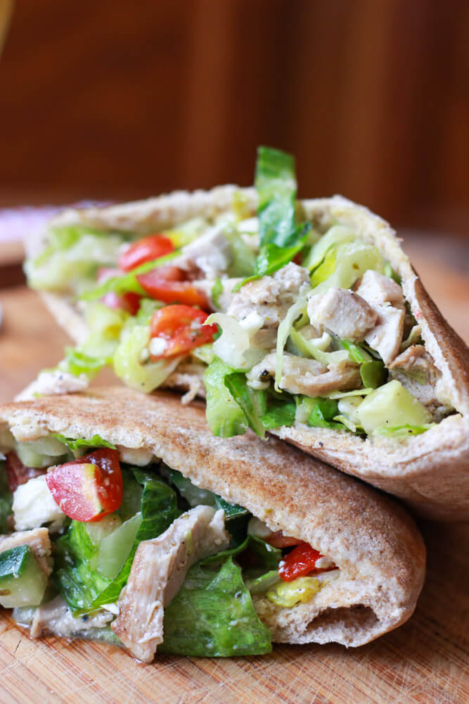 close up of Greek chicken and romaine salad stuffed inside a whole wheat pita.