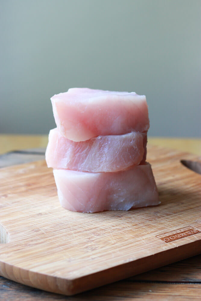 fresh albacore tuna stacked on a cutting board.