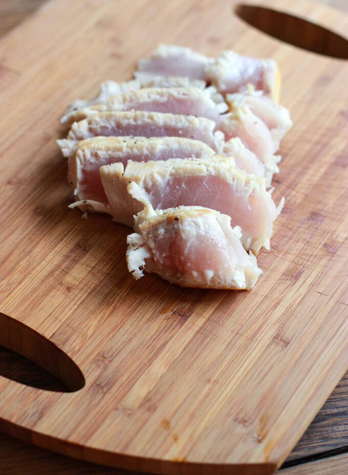 cooked tuna steaks thinly sliced on a board.