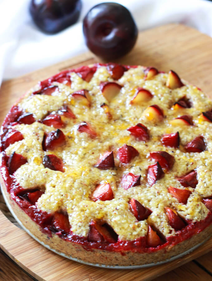 whole torte with fresh plums on a board.