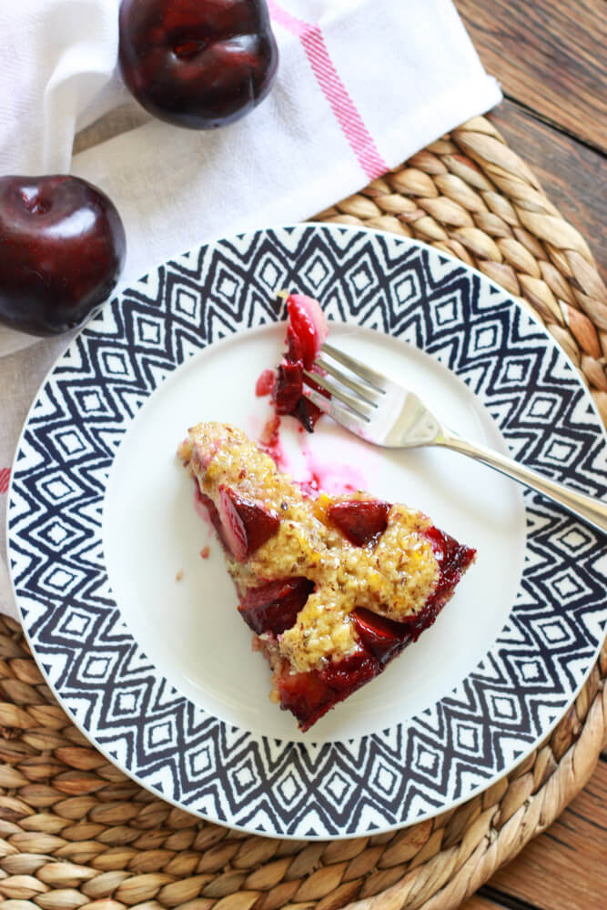 wedge of sliced plum torte on a plate with a side of fork.