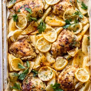 close up roasted chicken and potatoes in a baking pan