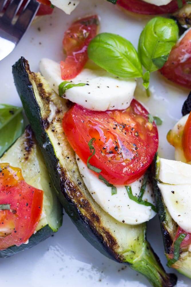 close up of grilled zucchini topped with caprese salad