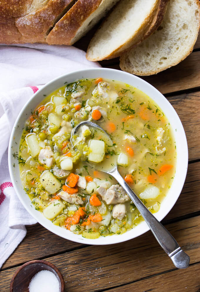 overhead of chicken split pea soup in white bowl with a side sliced bread on the side.