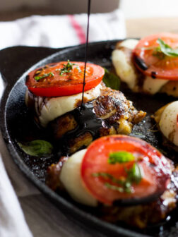 Side view balsamic glaze over caprese mozzarella chicken.