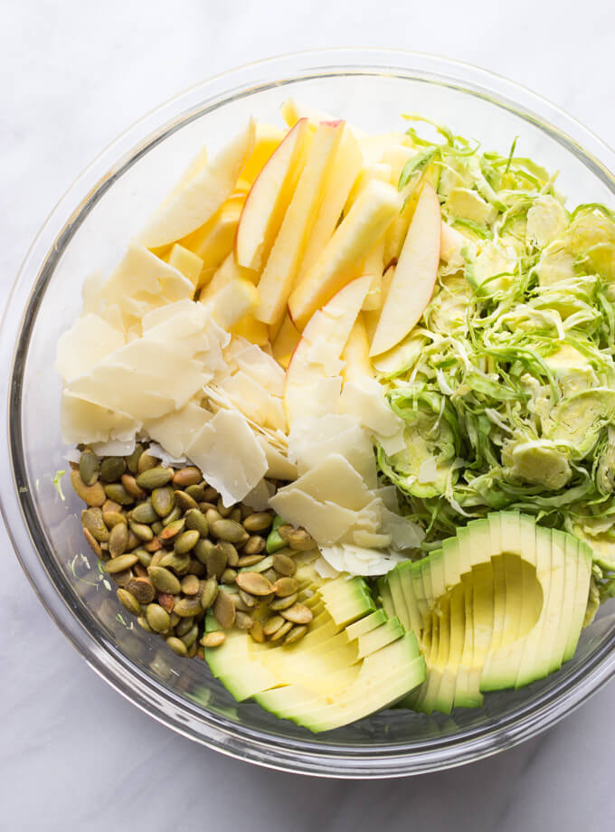 chopped up ingredients in a glass bowl for the brussels sprouts salad.