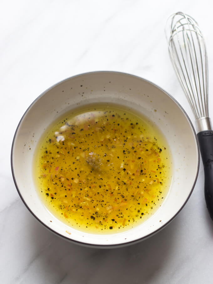 salad vinaigrette in a bowl with a side of whisk.