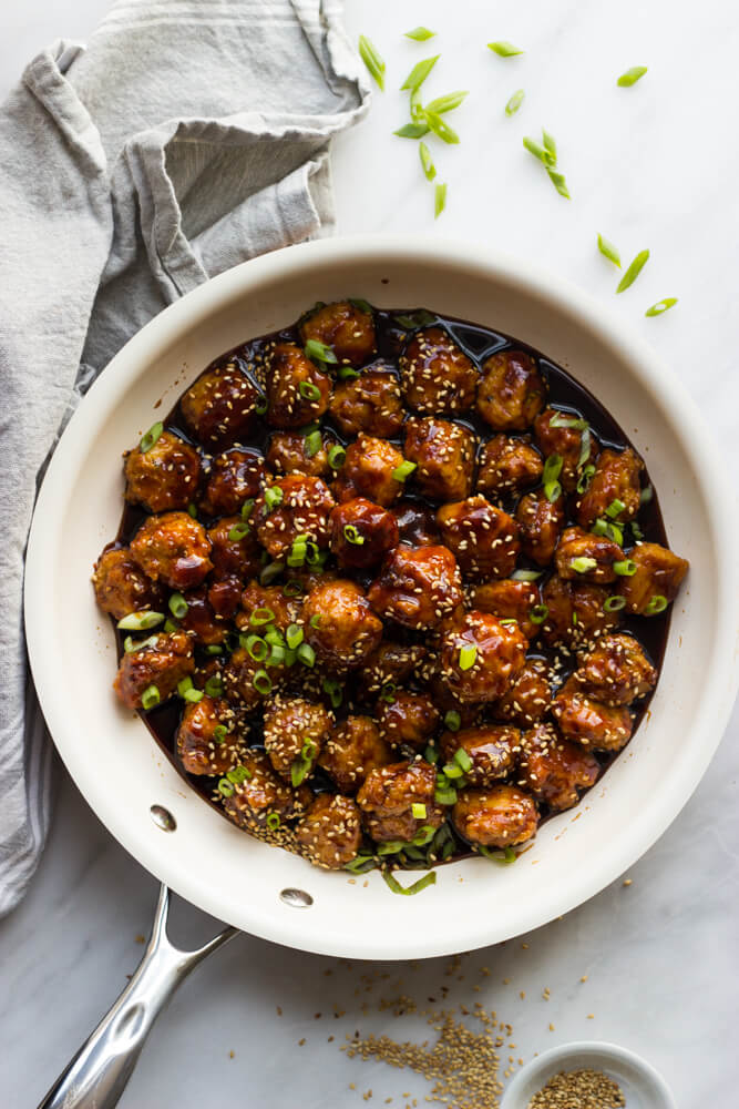 asian chicken meatballs in a skillet garnished with green onions.