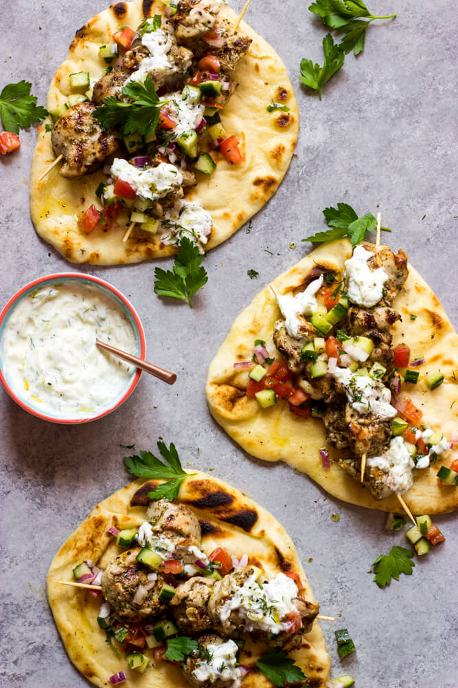 Overhead chicken gyro meat inside naan bread with tomato salad and tzatziki sauce