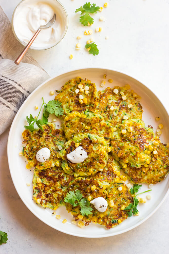 Overhead view of zucchini and corn fritters in white platter