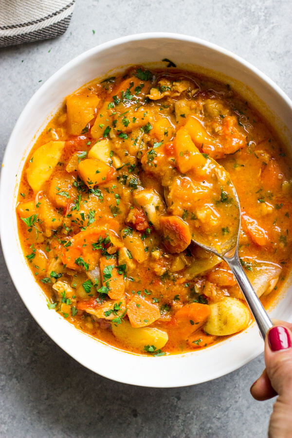 Overheat view of chicken stew in white bowl with spoon.