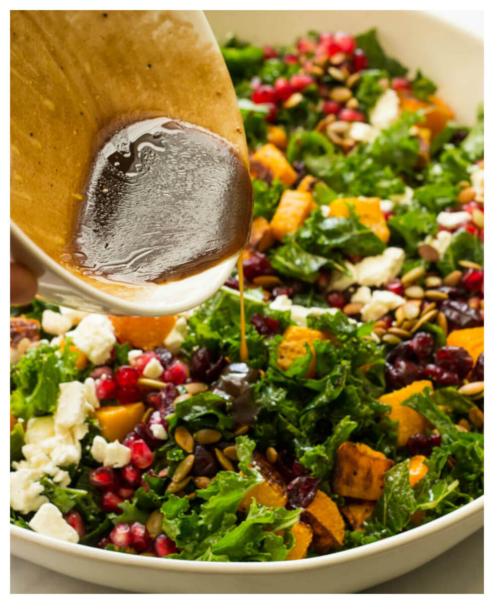 Close up of kale salad with dressing being poured