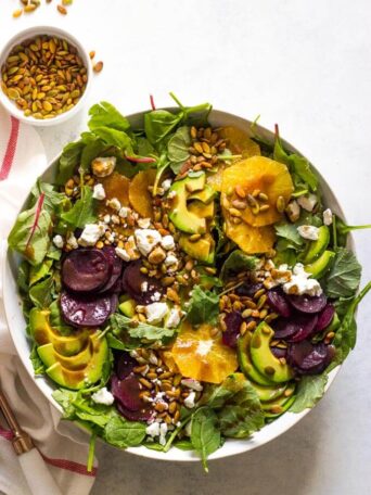 Overhead of roasted beet salad with avocado in white bowl