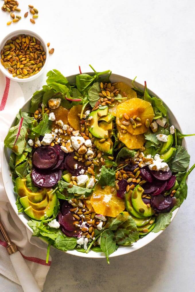 Overhead of roasted beet salad with avocado in white bowl