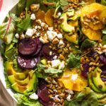 Close up of roasted beet salad with avocado in white bowl
