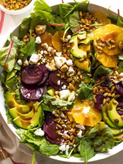 Close up of roasted beet salad with avocado in white bowl