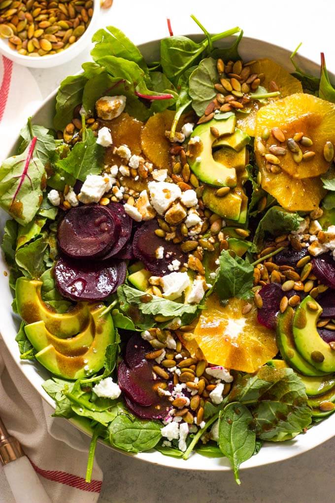 Close up of roasted beet salad with avocado in white bowl