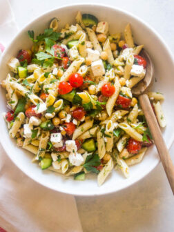 Cold pasta salad with italian dressing in white bowl and wooden spoon