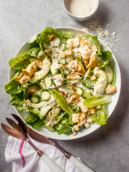 Caesar salad in a bowl with a side of dressing.