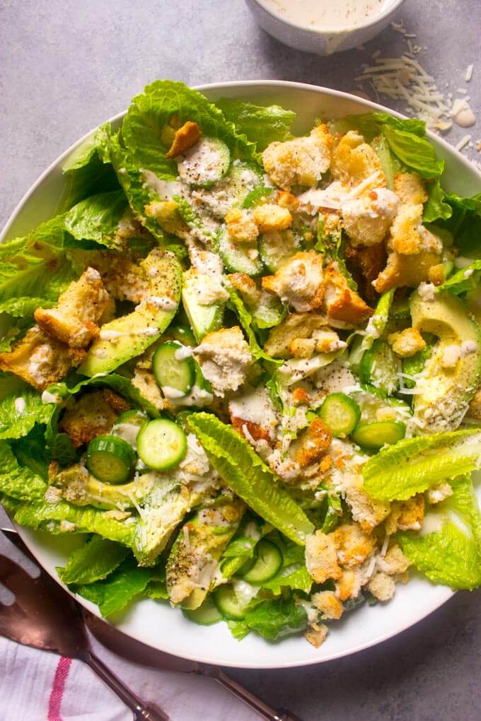 Close up avocado caesar salad with cucumbers in white bowl