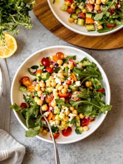 Overhead greek chickpea salad in white bowl on gray background