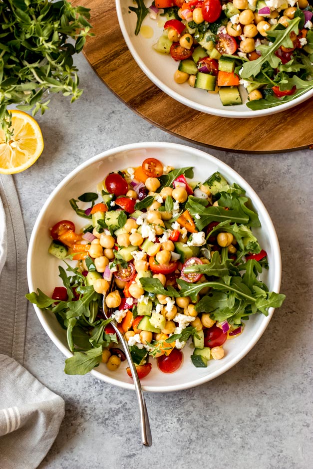 Overhead greek chickpea salad in white bowl on gray background