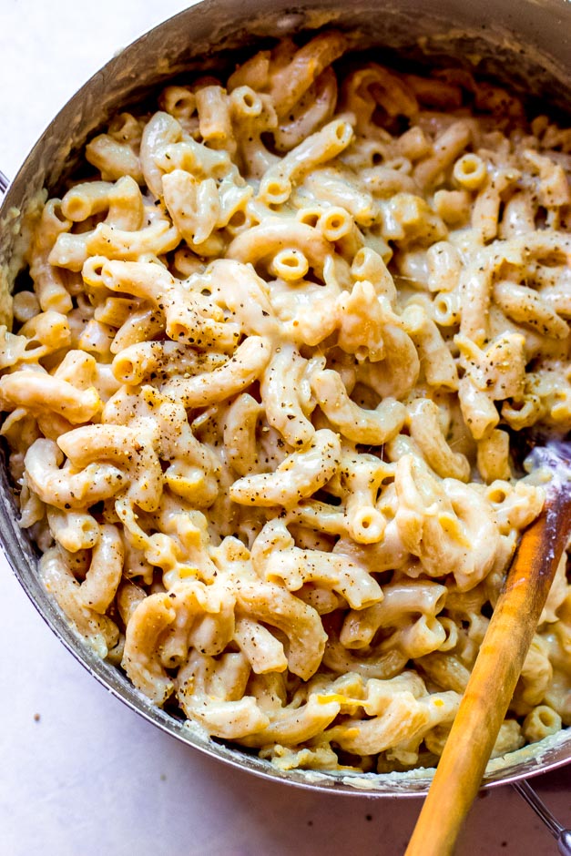 Overhead one pot mac and cheese in dutch-oven with wooden spoon