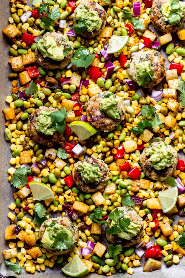 Close up of ground chicken patties topped with guacamole and served over corn succotash.