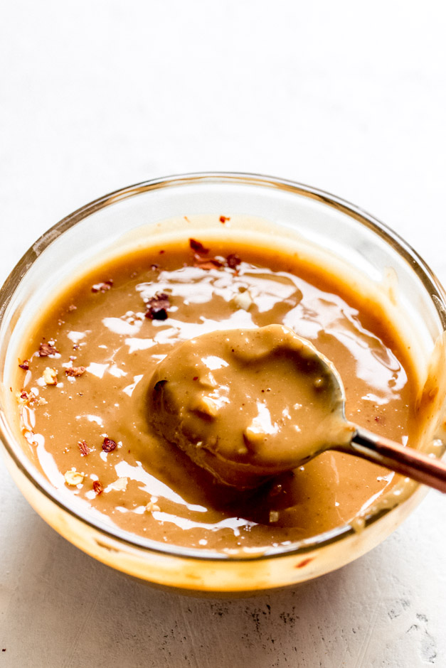 Close up of peanut sauce in glass bowl with spoon