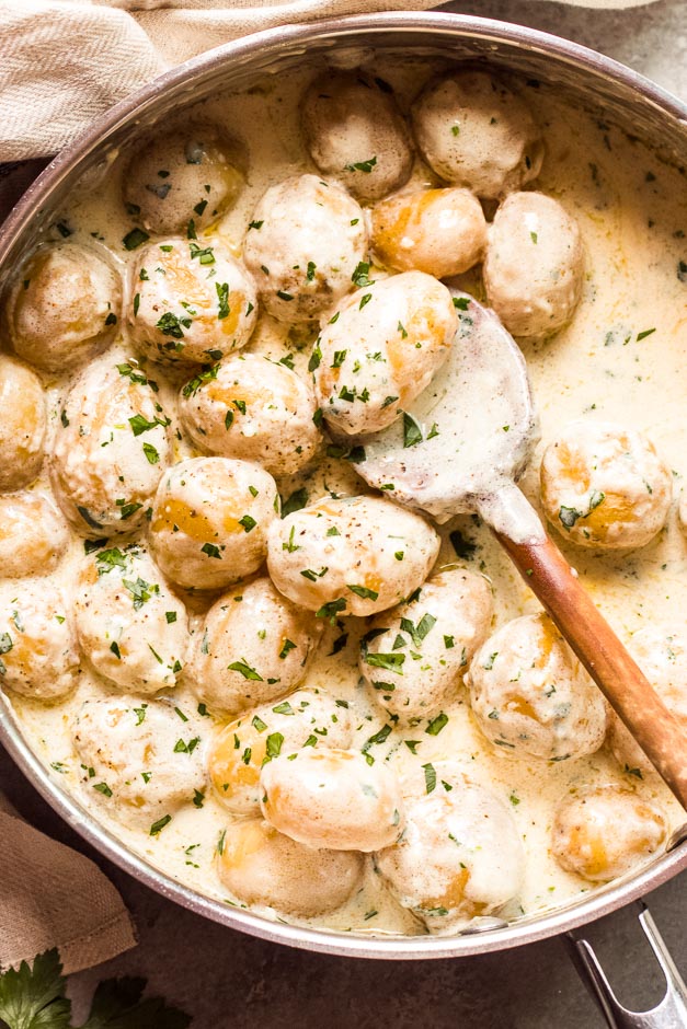 Overhead new potatoes in cream sauce in skillet 