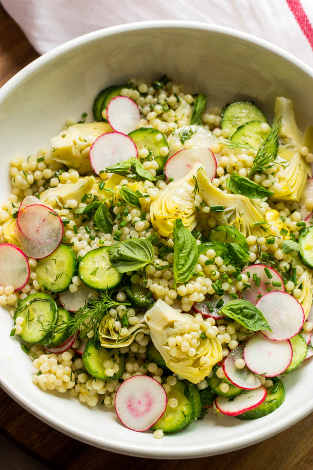 Close up Israeli couscous salad with marinated artichokes in white bowl