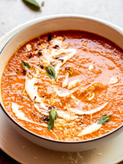 Close up roasted tomato basil soup in white bowl