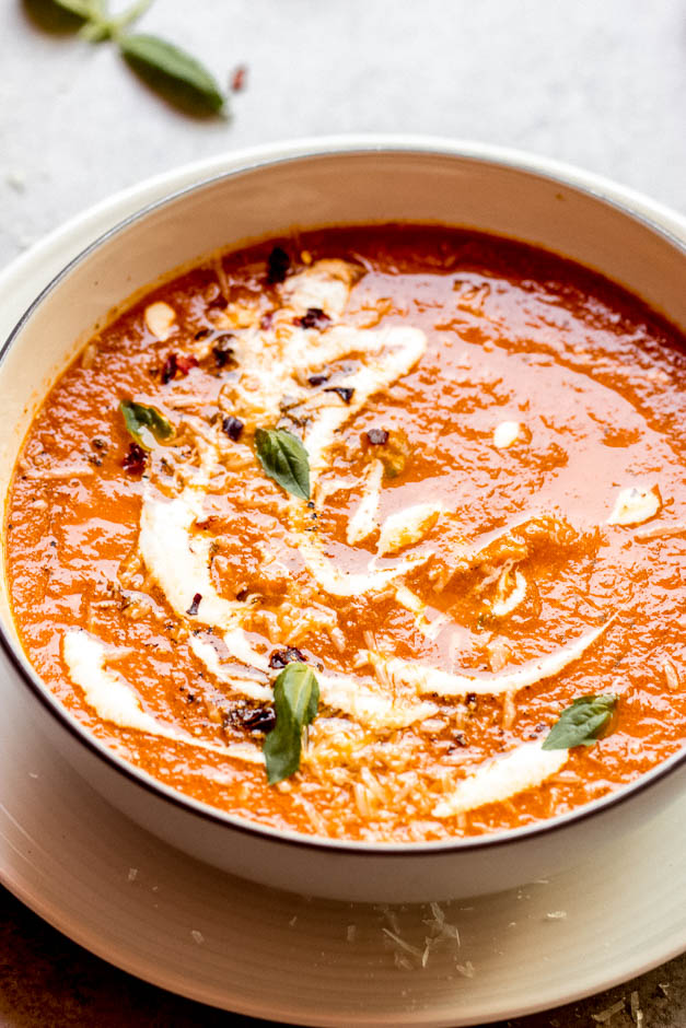 Close up roasted tomato basil soup in white bowl.