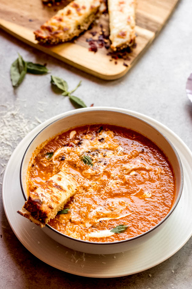 Overhead tomato soup recipe with breadstick dunked in.