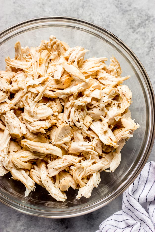 close up shredded roasted chicken breast in a glass bowl.