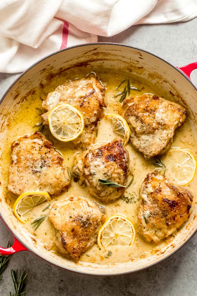 honey mustard chicken thighs with sliced lemons in a saute pan.