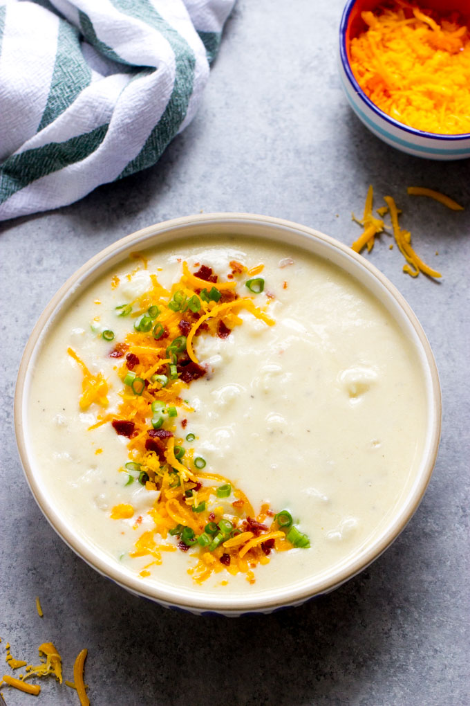 quick and easy potato soup in a white bowl garnished with cheese, bacon, and green onions.