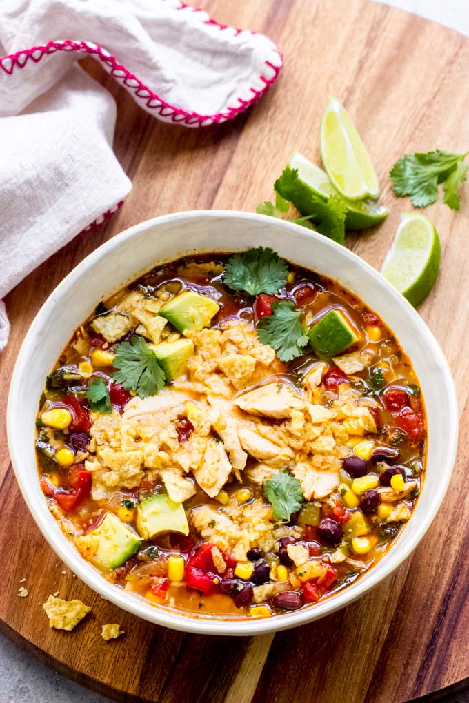 turkey tortilla soup in a bowl topped with avocado and crushed tortillas.