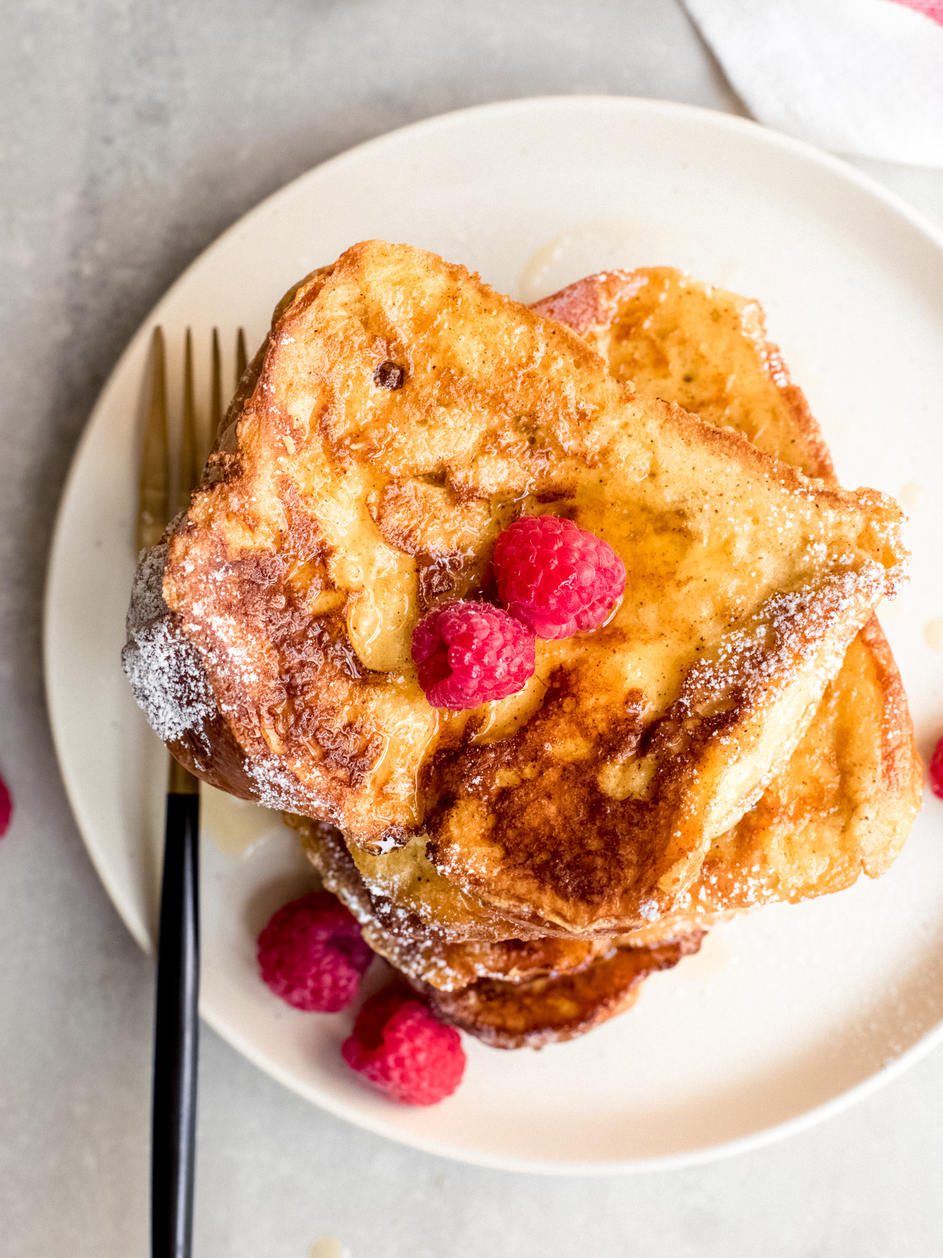 close up of french toast with brioche bread on a plate with a side of fork.