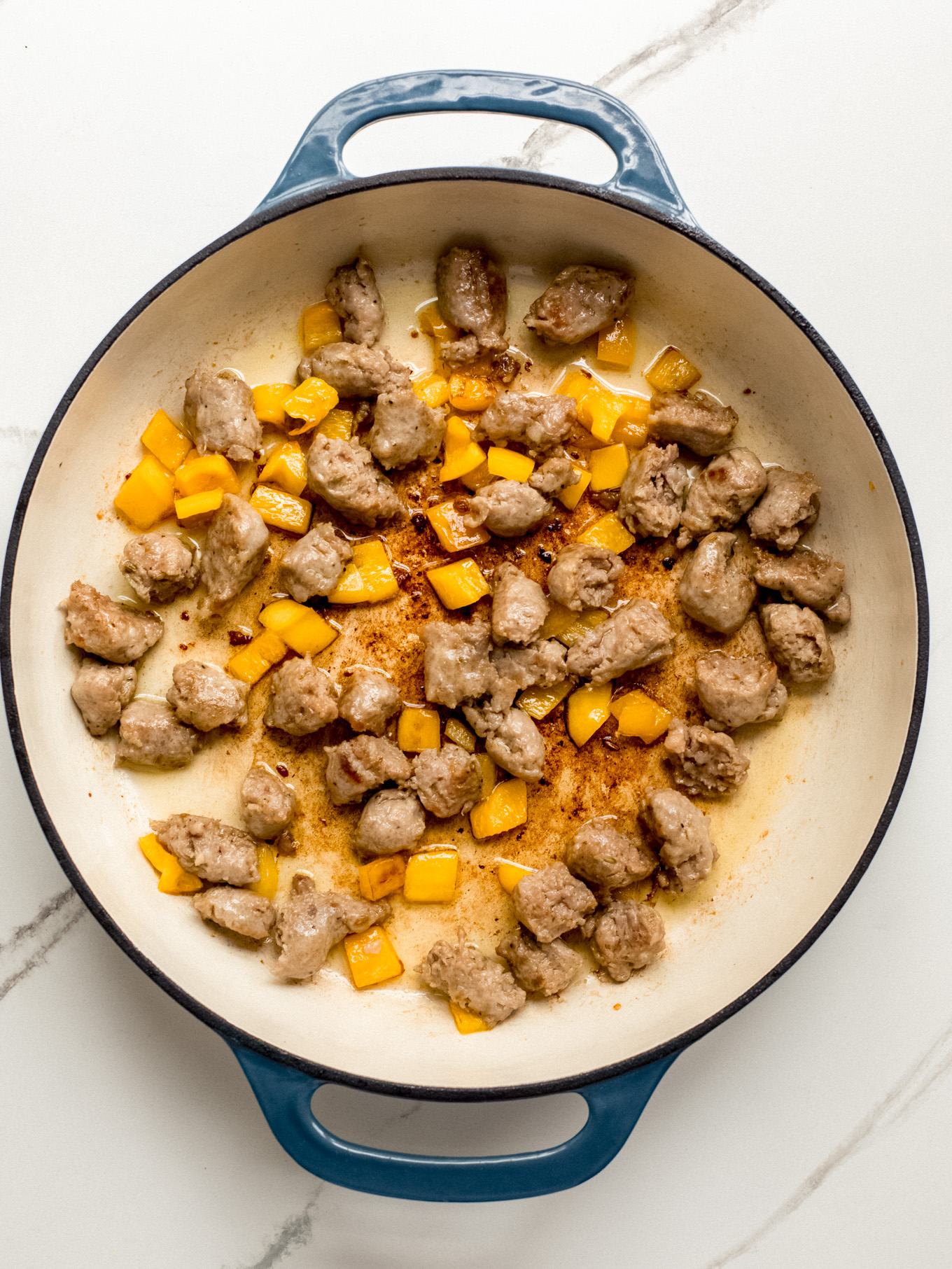 cooked Italian sausage and bell pepper in a saute pan.