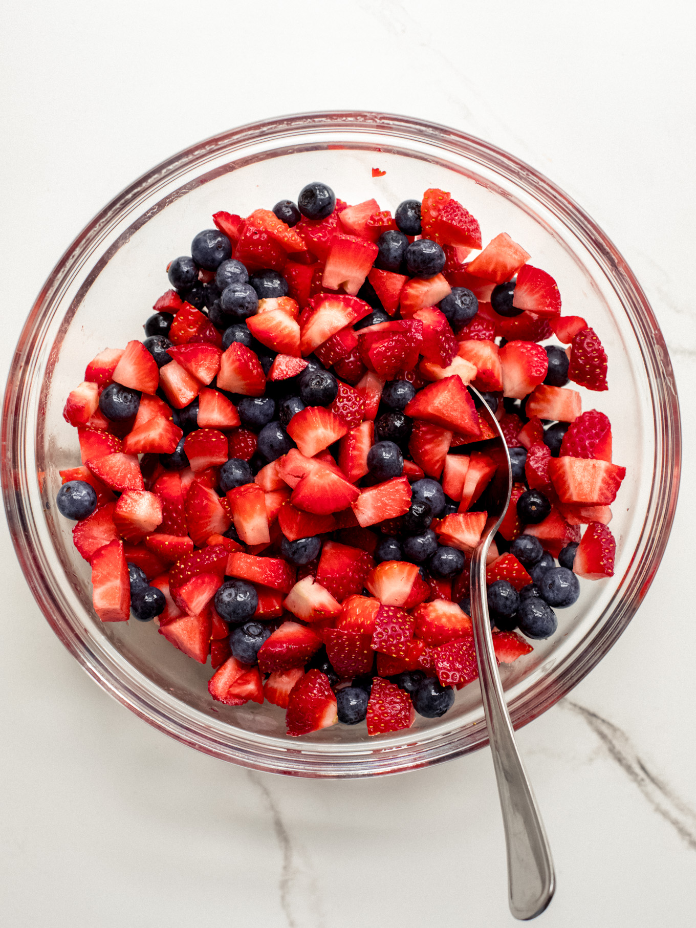 mixed chopped strawberries and blueberries in a glass bowl.