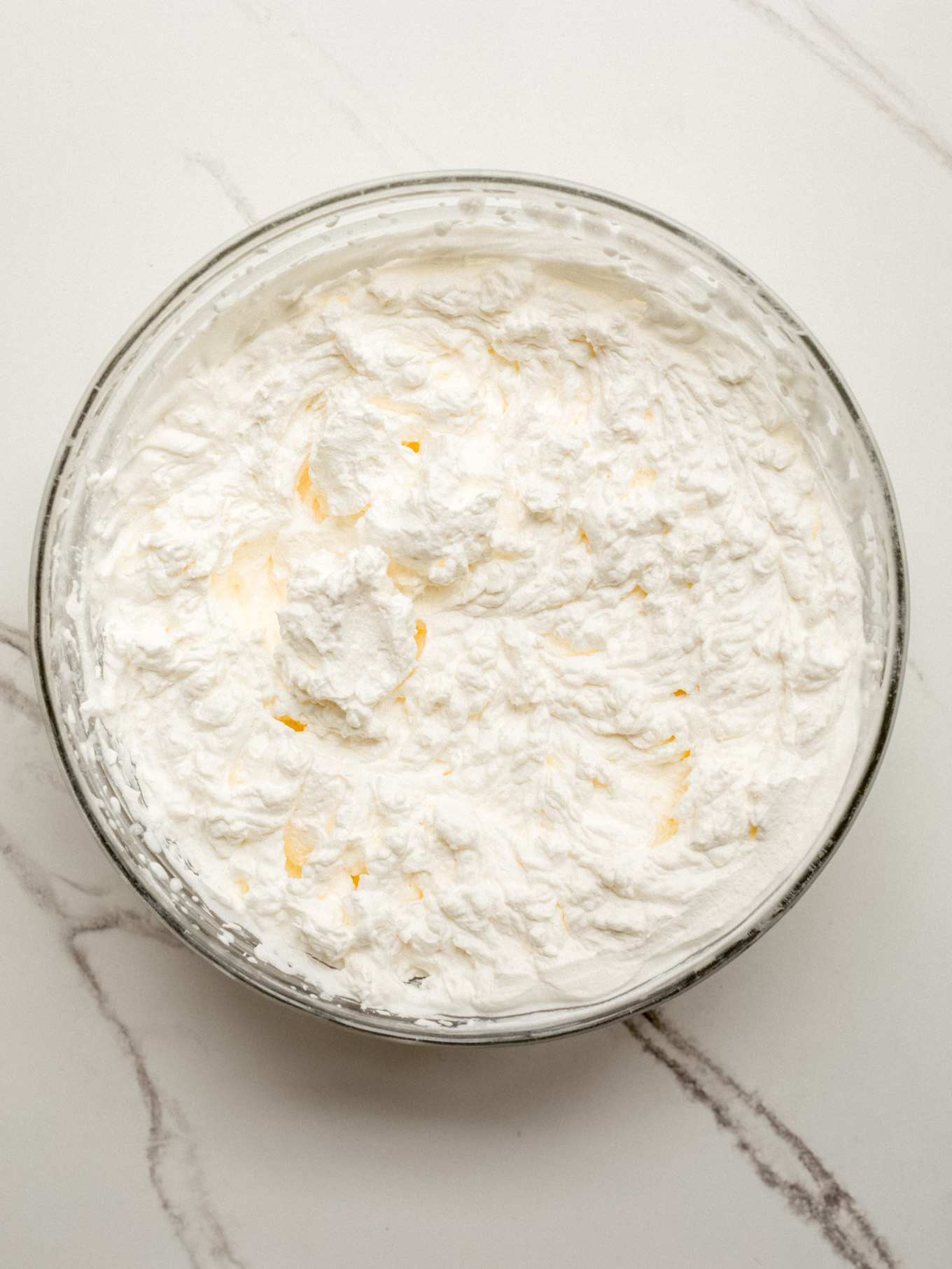 whipped heavy cream in a glass mixing bowl.