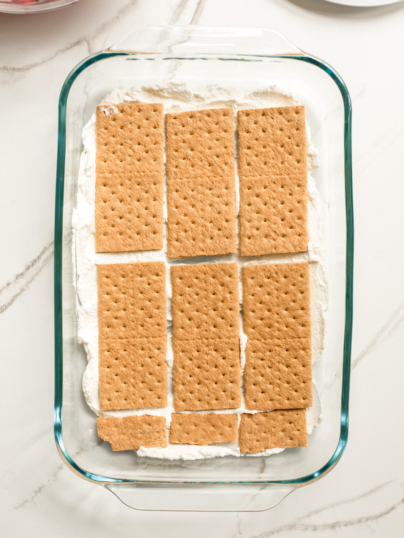 layered whipped cream and graham crackers in a glass baking dish.