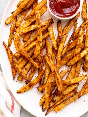 old bay fries on white platter with side of ketchup.