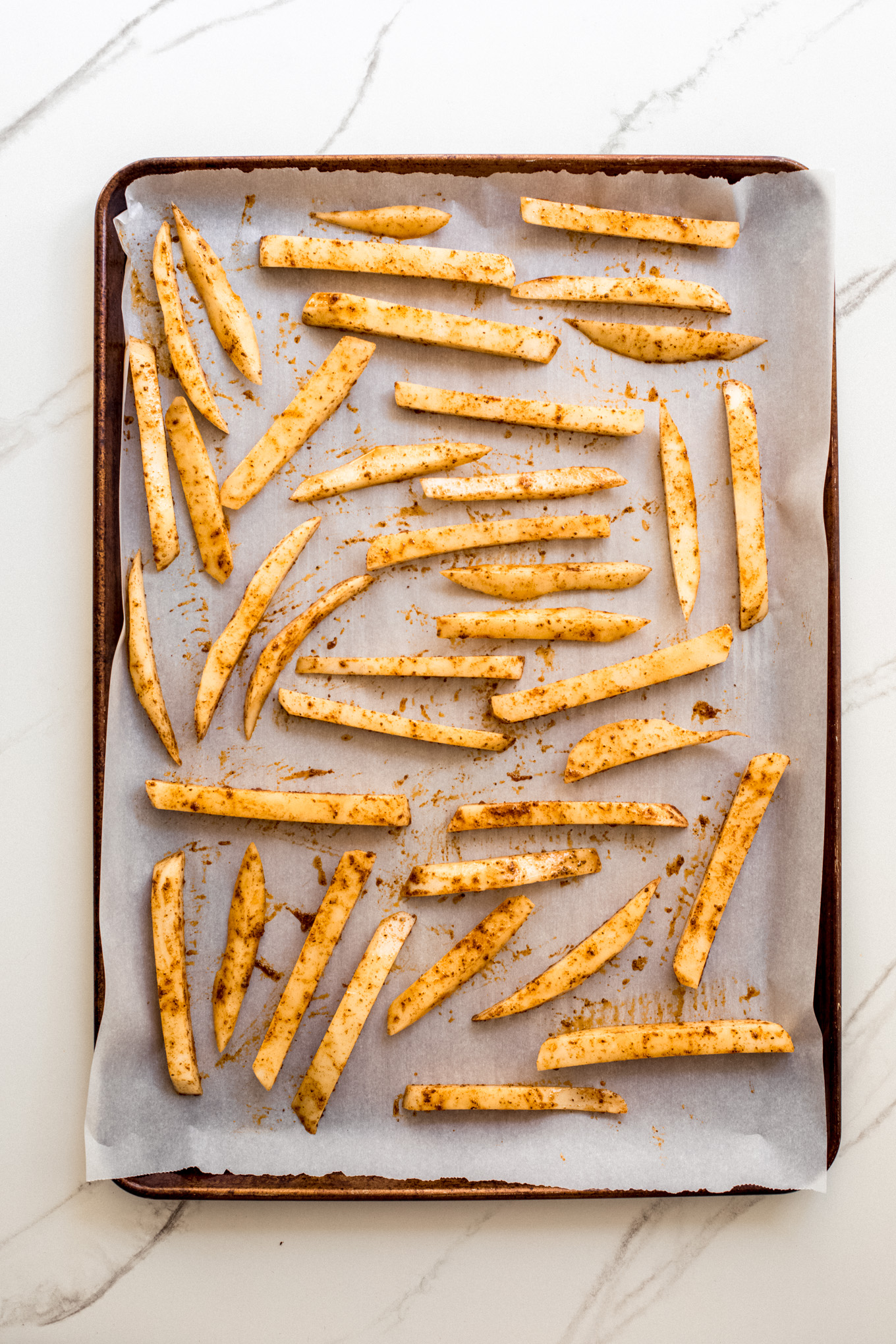 french fries on a baking sheet lined with parchment paper.