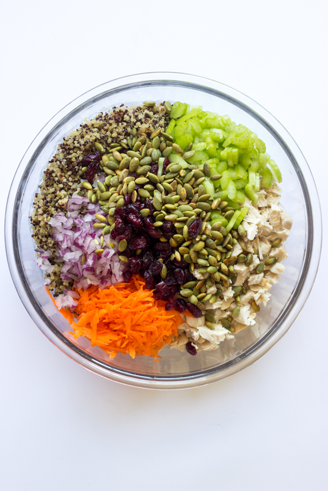 cooked quinoa with chopped vegetables and cooked chicken inside a glass bowl.