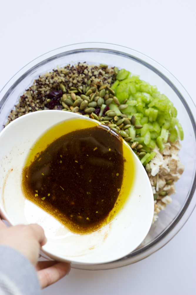 dressing being poured over quinoa salad.