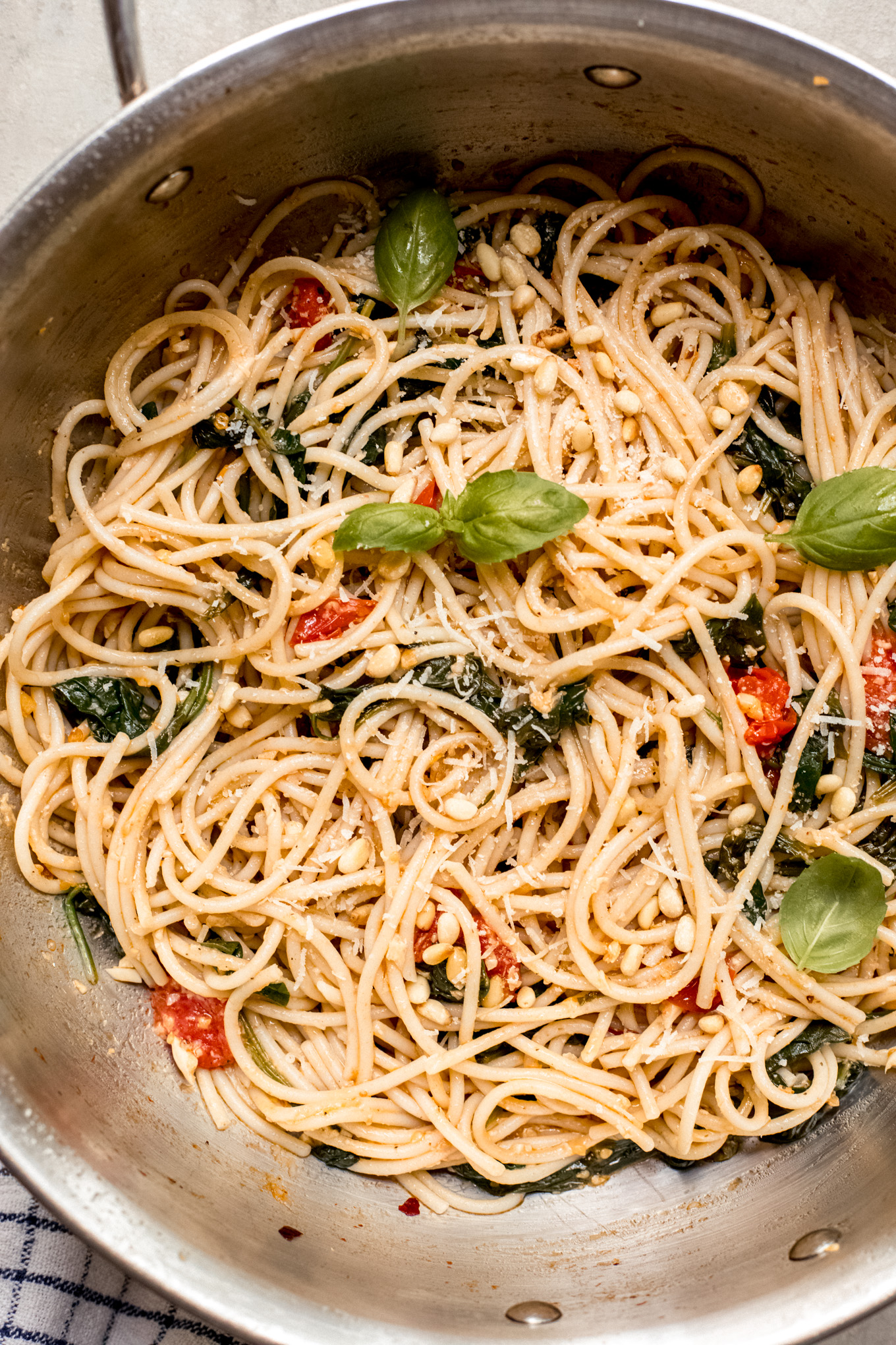 spaghetti with tomatoes and spinach in a saute pan.