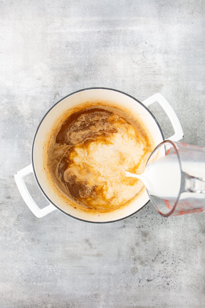 milk being poured into a dutch oven.