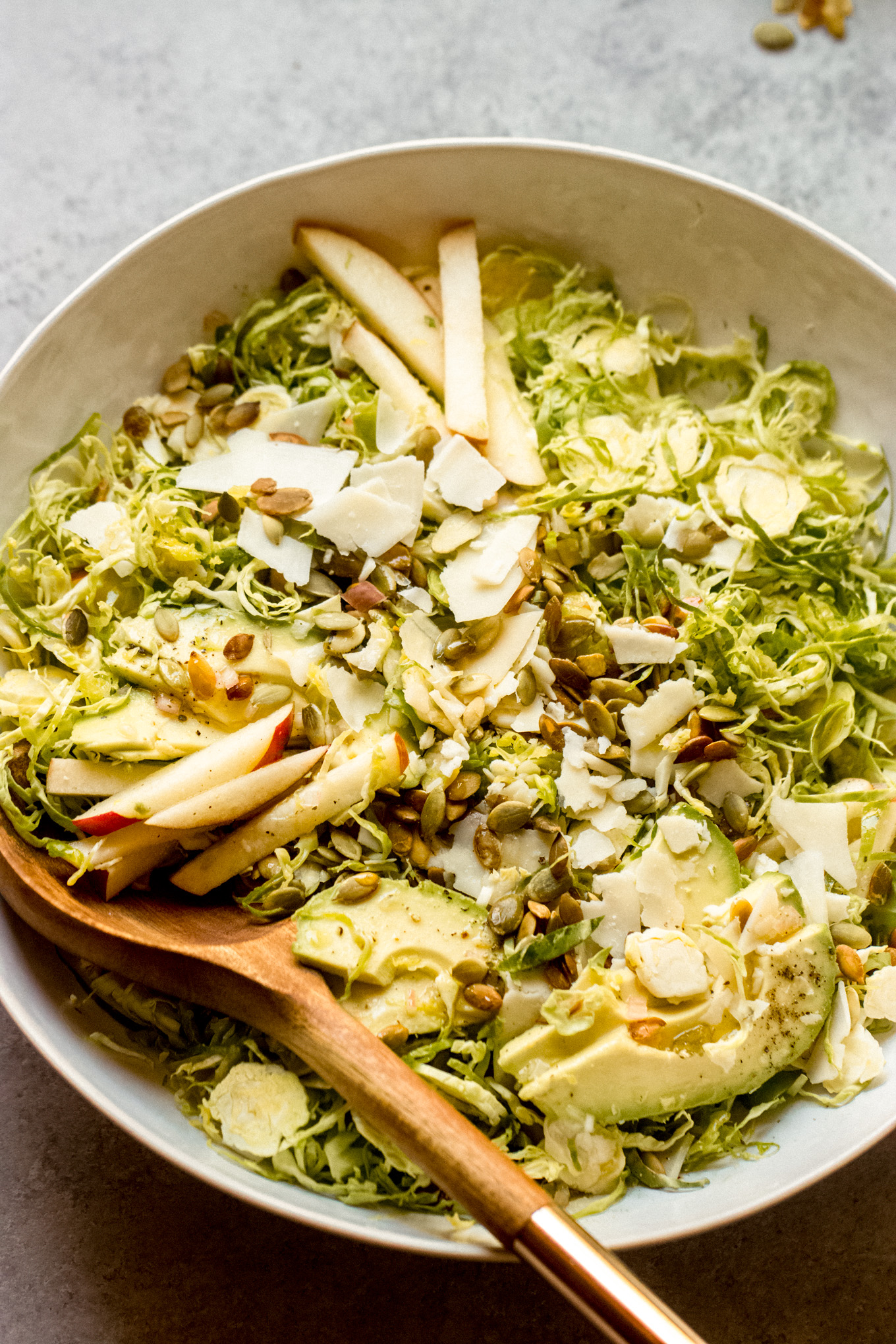 salad with shredded Brussels sprouts with sliced apples and avocado in a bowl.